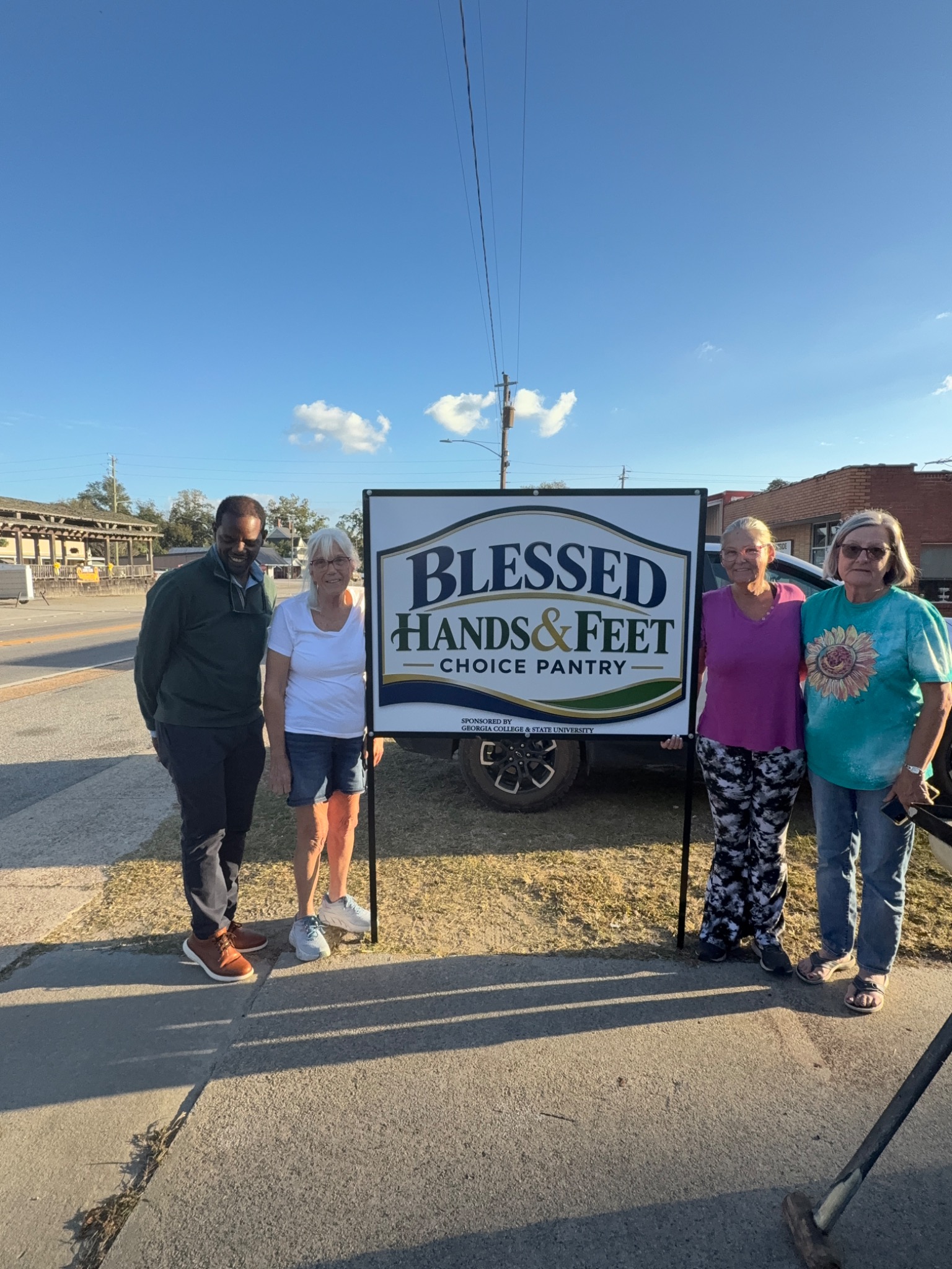 Community volunteers standing beside the Blessed Hands and Feet Choice Pantry sign